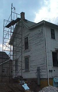 scaffolding along south side of house up to the chimney on the roof peak