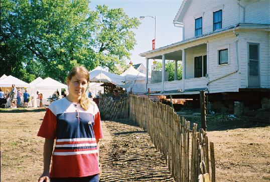 Yulia stands beside the snowfence at the side of the house.