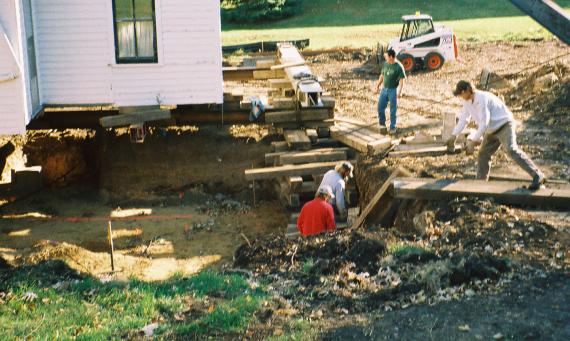 building movers lay wood beams in hole to form supportive crib