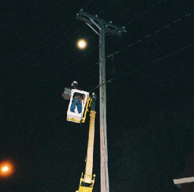 near-full moon over cable worker lifted in cherry picker