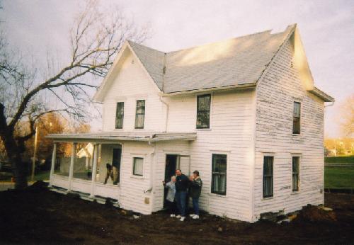 view of the house, newly on its foundation, from the southwest, with Travis on porch and Grandma, Ken and Colleen exiting
