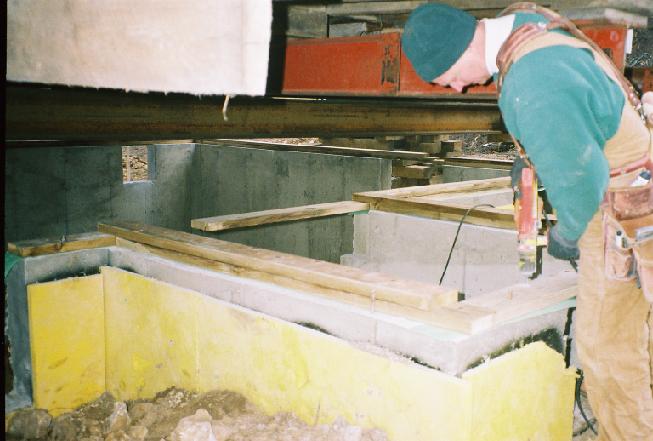 The carpenter covers the top of the foundation wall with two layers of wooden sill beams, on which the house will sit.