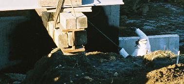 man in the white suit in the trench, spraying a coat of waterproofing on the outside of the walls
