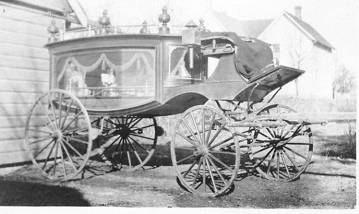 Gesme hearse carriage, with rear of home in background