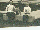 two children with a dog, all seated on the carriage step